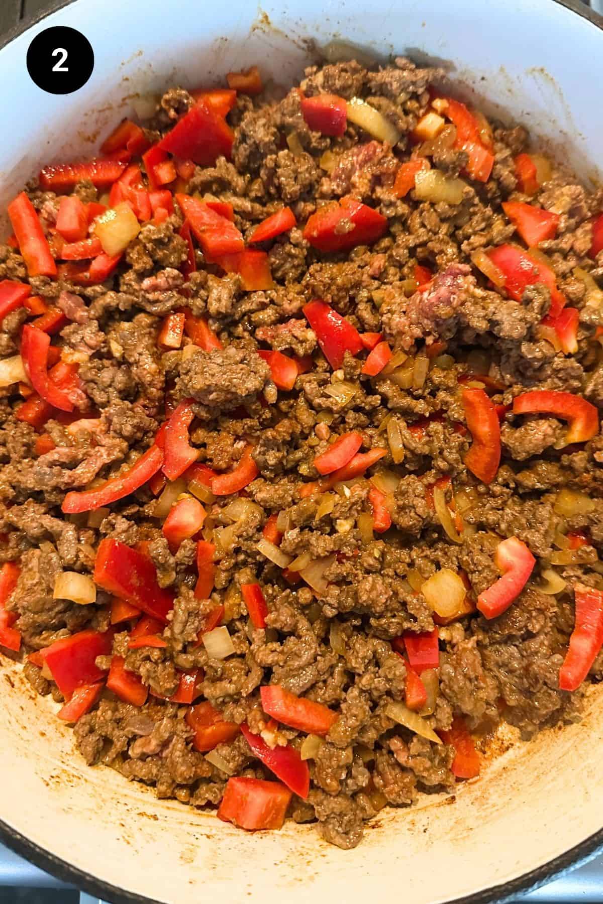 Ground beef mixture with red peppers in a Dutch oven casserole.