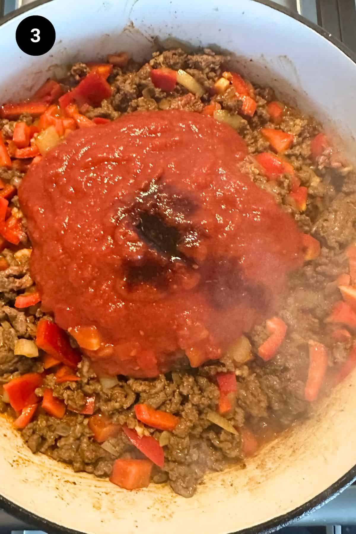 Tomatoes added to ground beef mixture.