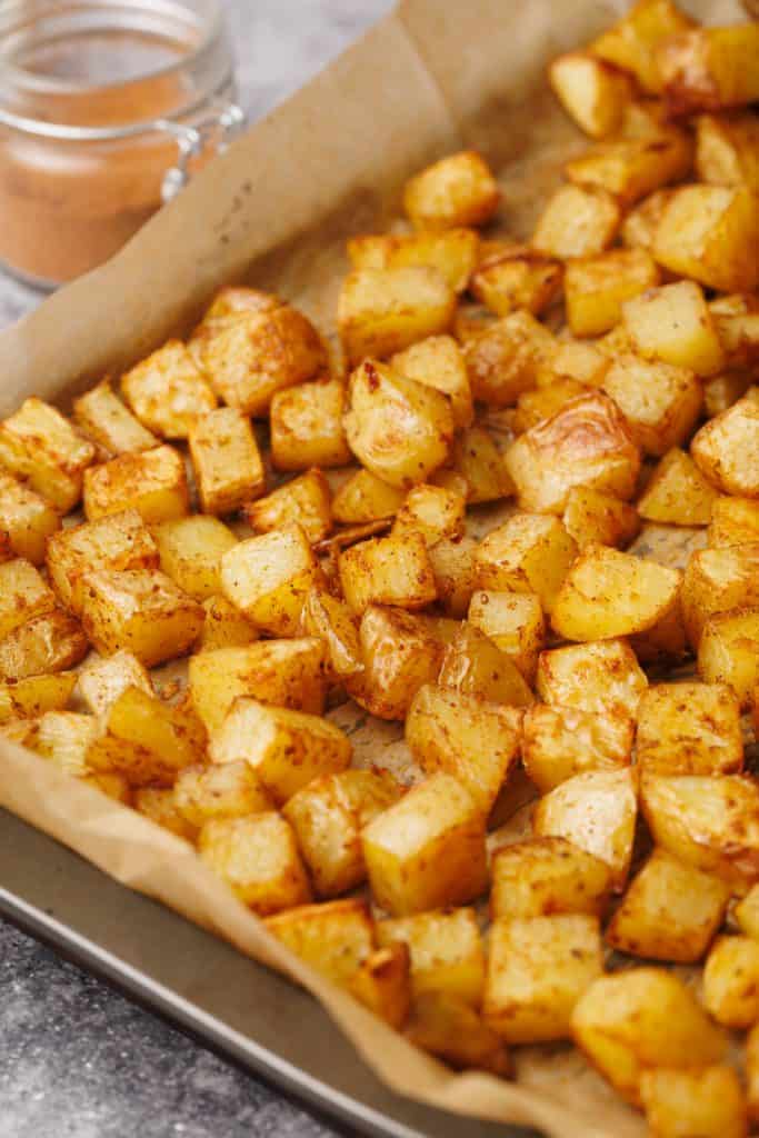A tray of taco potatoes next to a jar of taco seasoning.