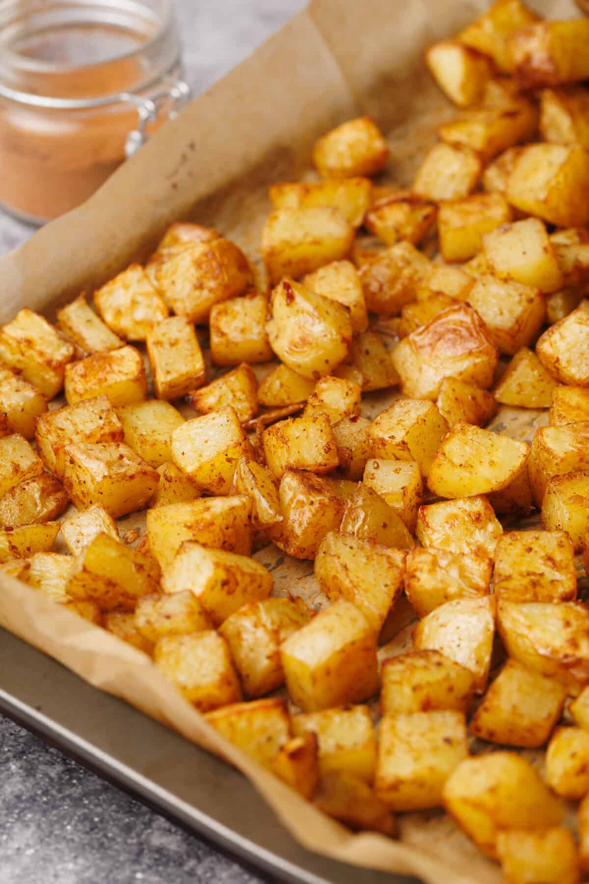 A tray of taco potatoes next to a jar of taco seasoning.