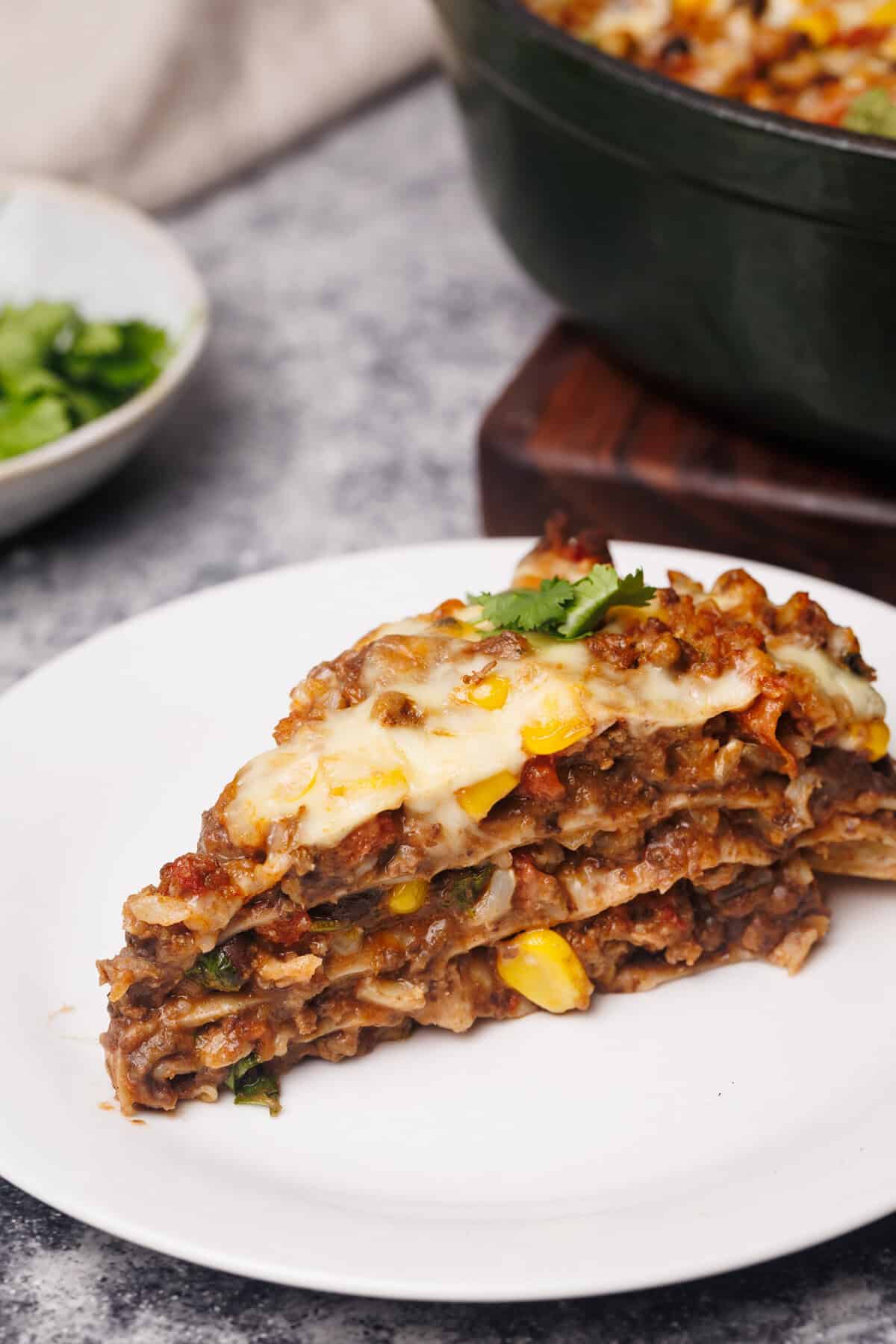 A slice of Mexican Lasagna on a white plate.