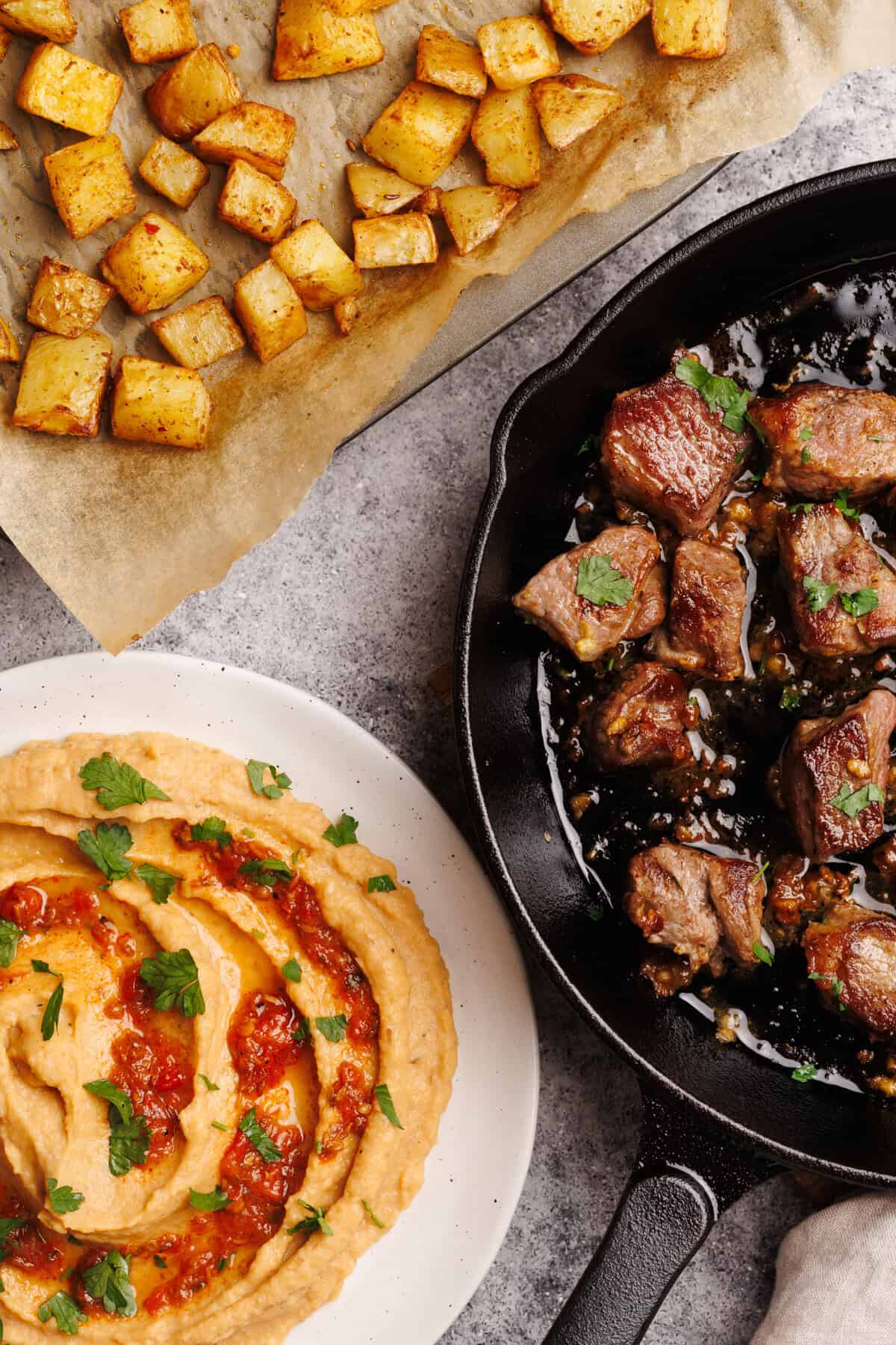 Taco potatoes next to steak bites and hummus.