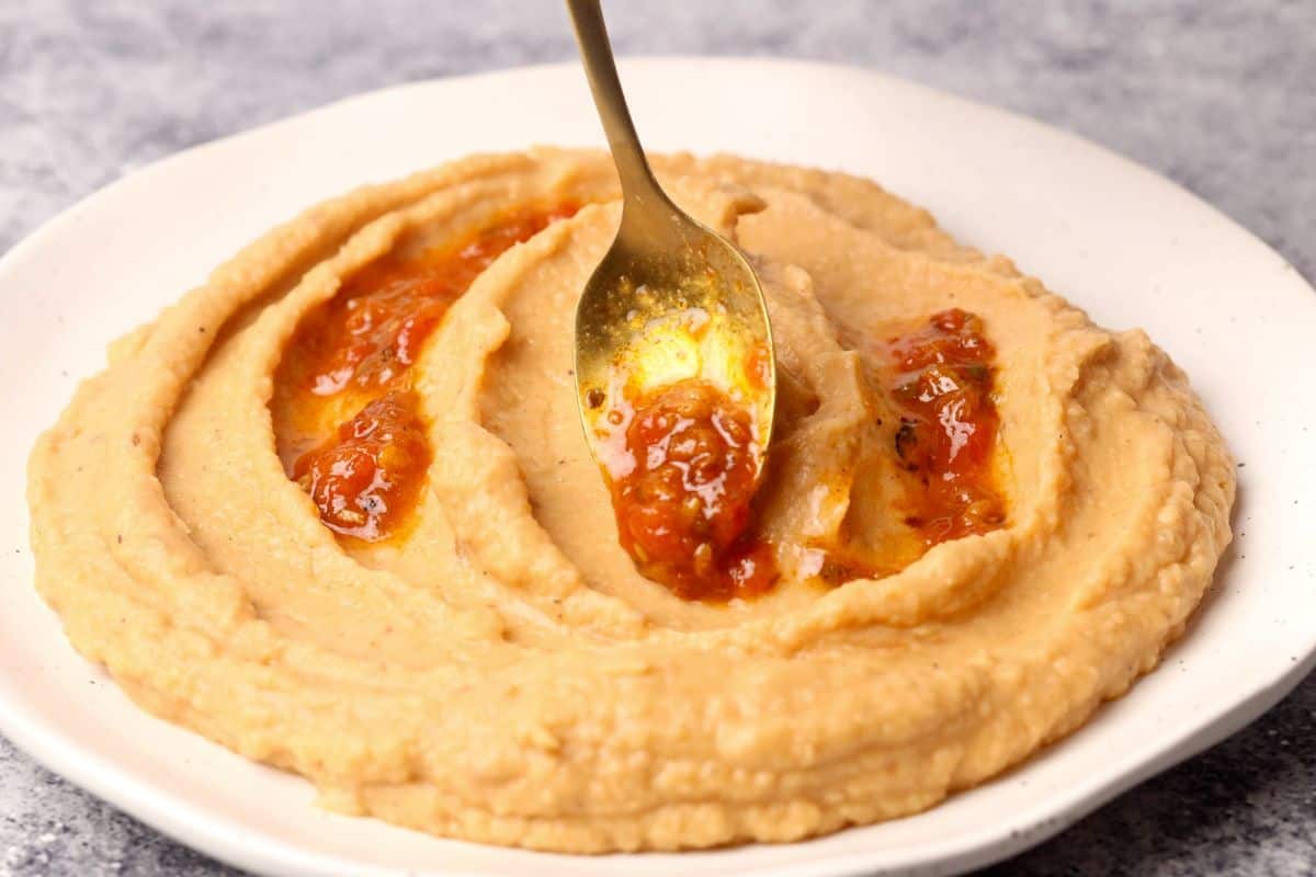 Harissa being added to the hummus.