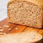 A loaf of whole grain spelt bread on a wooden board.