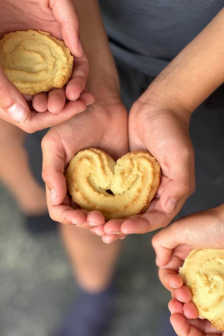 A child's hand holding a spritz cookie.